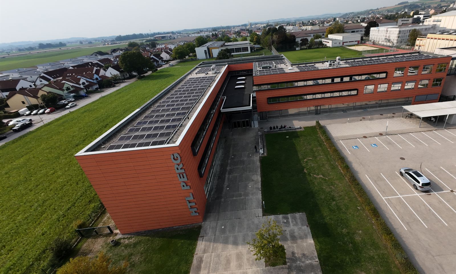 Die HTL Perg aus der Luft: Schulgebäude mit Haupteingang und Photovoltaik am Dach