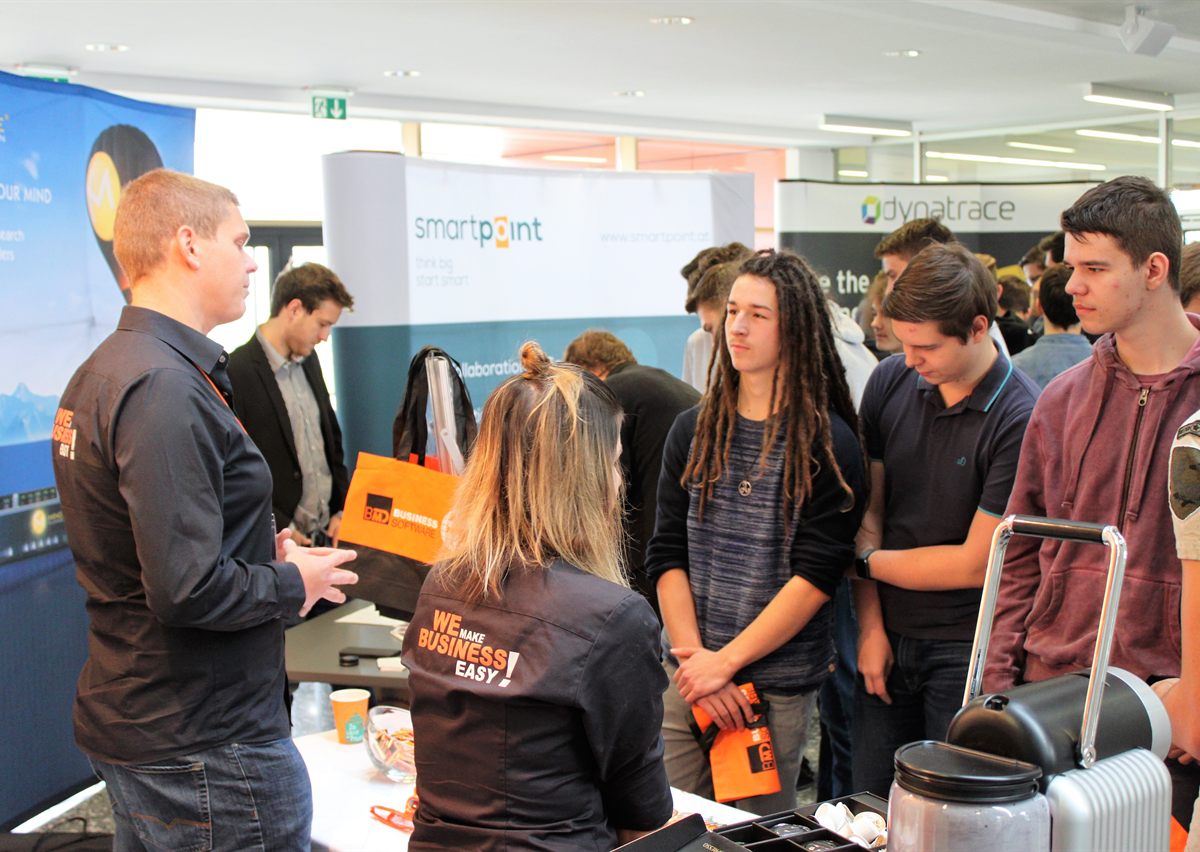 Schüler im Gespräch mit Firmenvertreter:innen an einem Messestand beim FIT