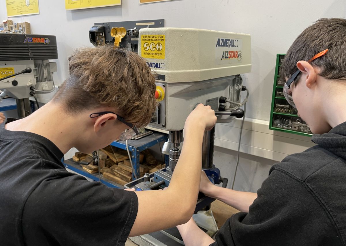 Schüler mit Schutzbrille an einer Säulenbohrmaschine in der Werkstatt