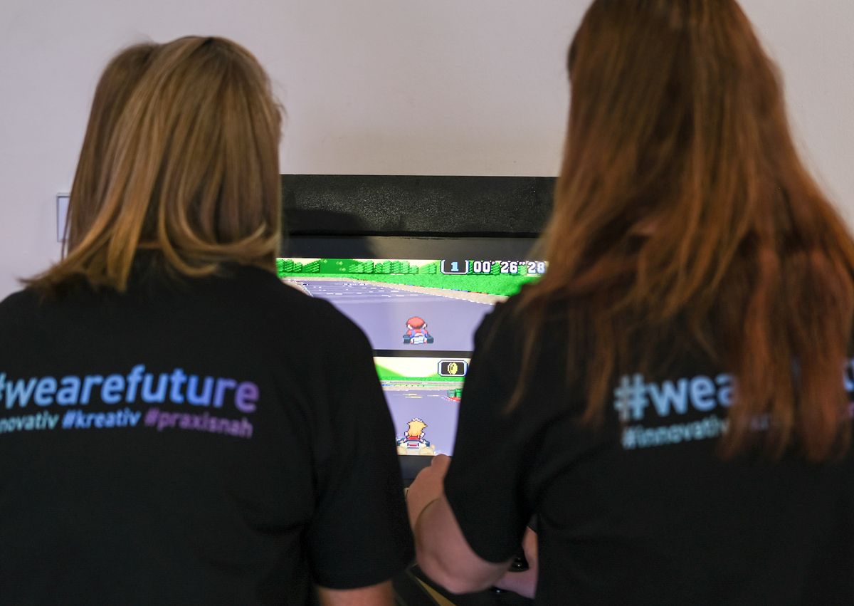 Zwei Schülerinnen in #wearefuture-Shirts spielen gemeinsam am Arcade-Automaten